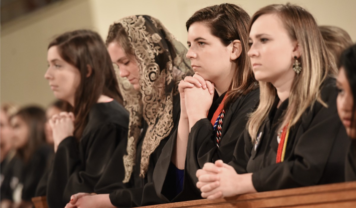 Graduates praying at Baccalaureate Mass