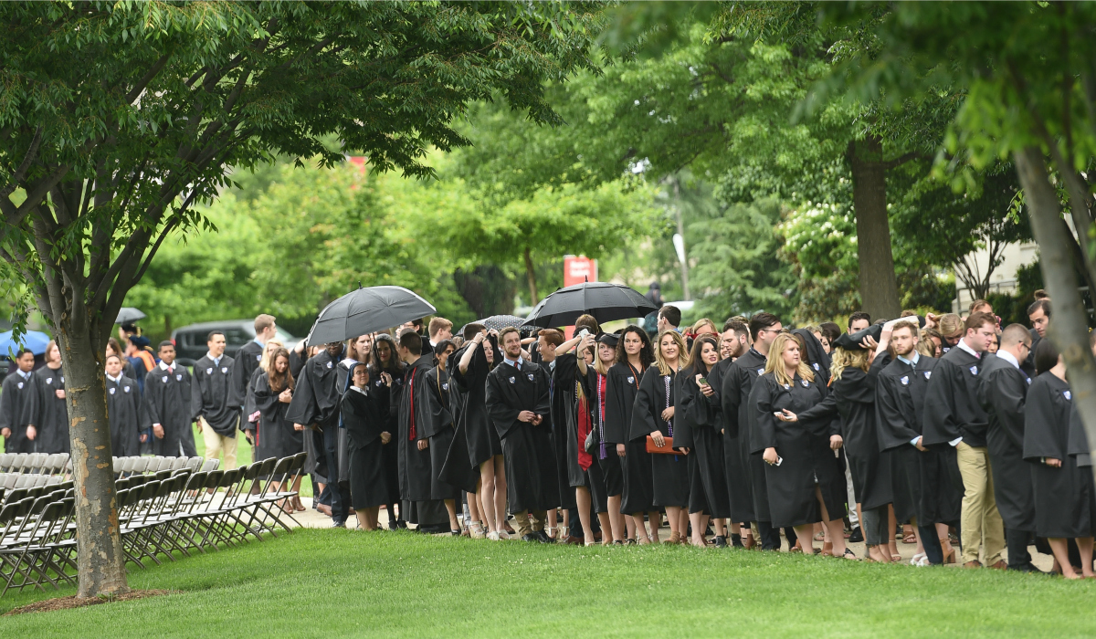 Graduates standing under umbrellas